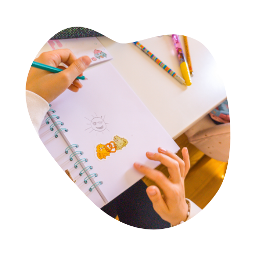 Enfant qui dessine sur un cahier à spirale du coin des momotes.