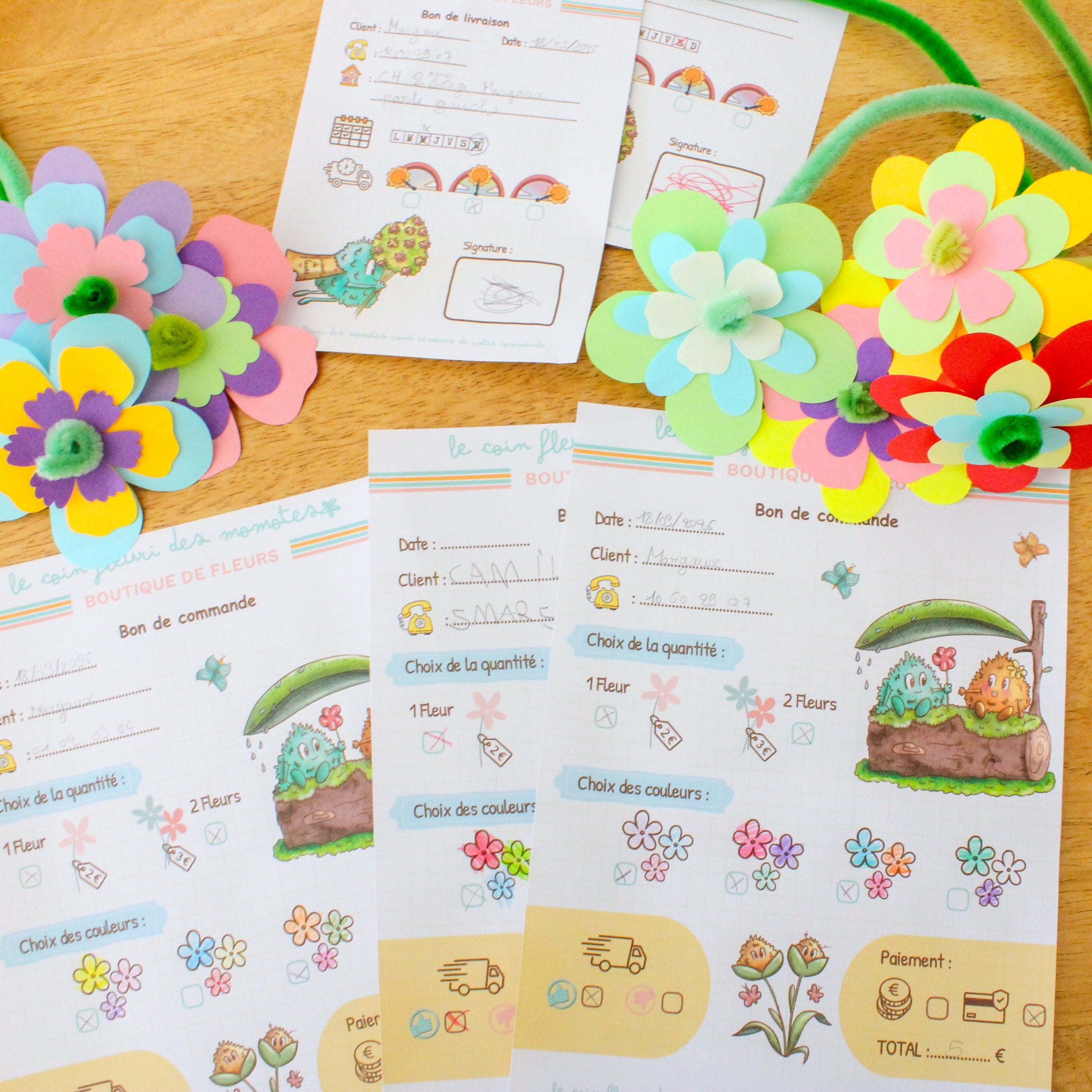 Photo des supports du jeu symbolique fleuriste avec les bons de livraison, les bons de commande, et les fleurs réalisées.