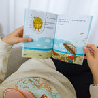 Enfant qui utilise le marque page cupcake momote sur le l'histoire de Crabe le rouge et les momotes à la plage.
