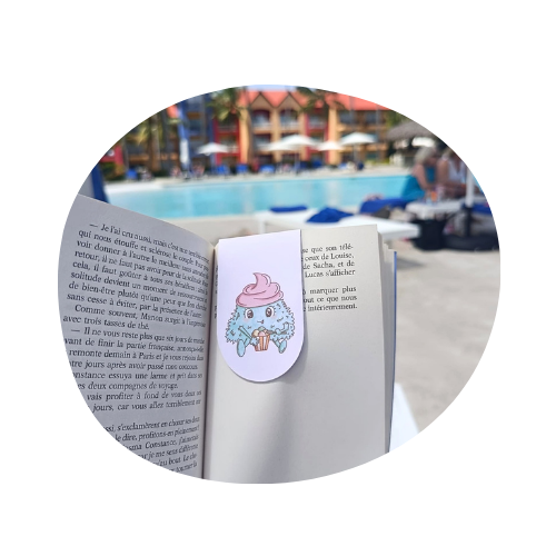 Le marque page de Creamy Momote sur un livre lors d'une lecture en bord de piscine.