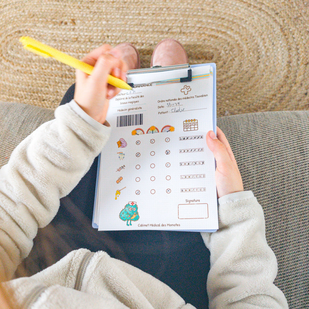 Photo d'une enfant qui remplit une ordonnance du kit de papeterie pour jouer au médecin.